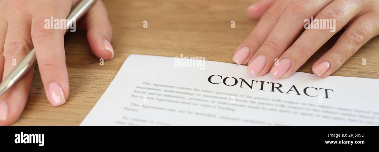 Female manager asks client to sign contract in her office. Close up of woman's hands with agreement and pen on table. Stock Photo