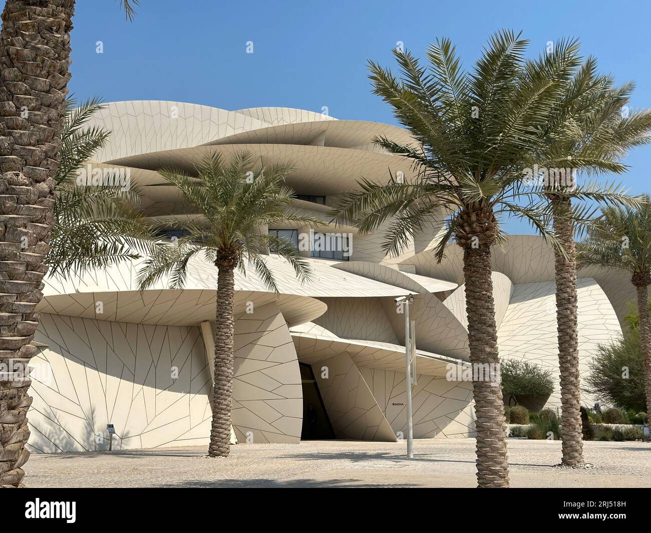 The National Museum of Qatar surrounded by tall palm trees with a ...