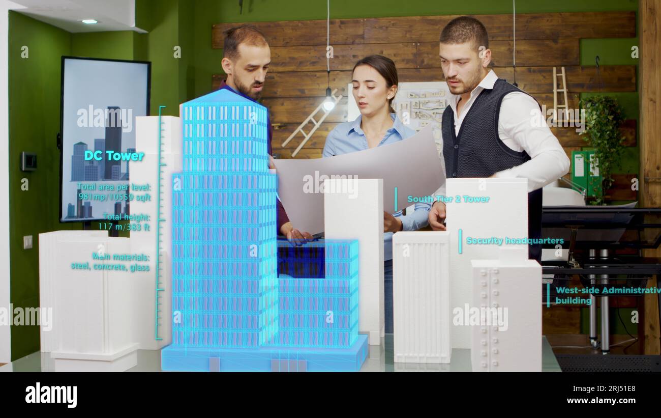Construction developing coworkers in office looking over blueprint ...