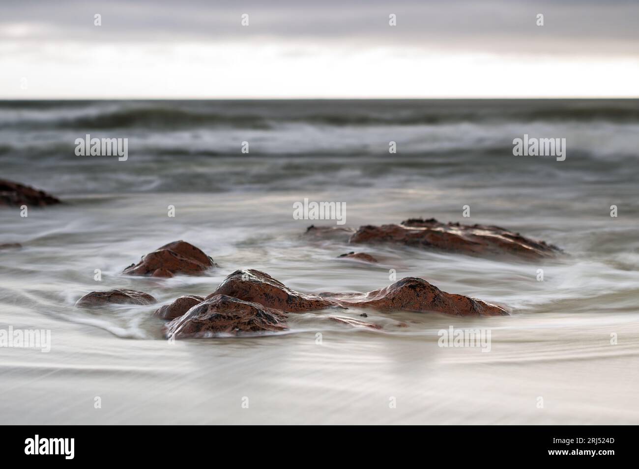 Waves breaking over rocks slow shutterspeed tilt-shift landscape photography Stock Photo