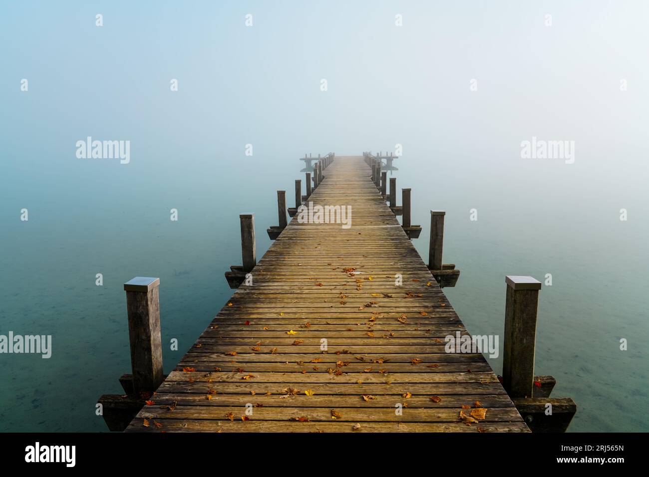 Jetty in the fog. Mystical foggy landscape at the lake. Morning fog in autumn. Stock Photo