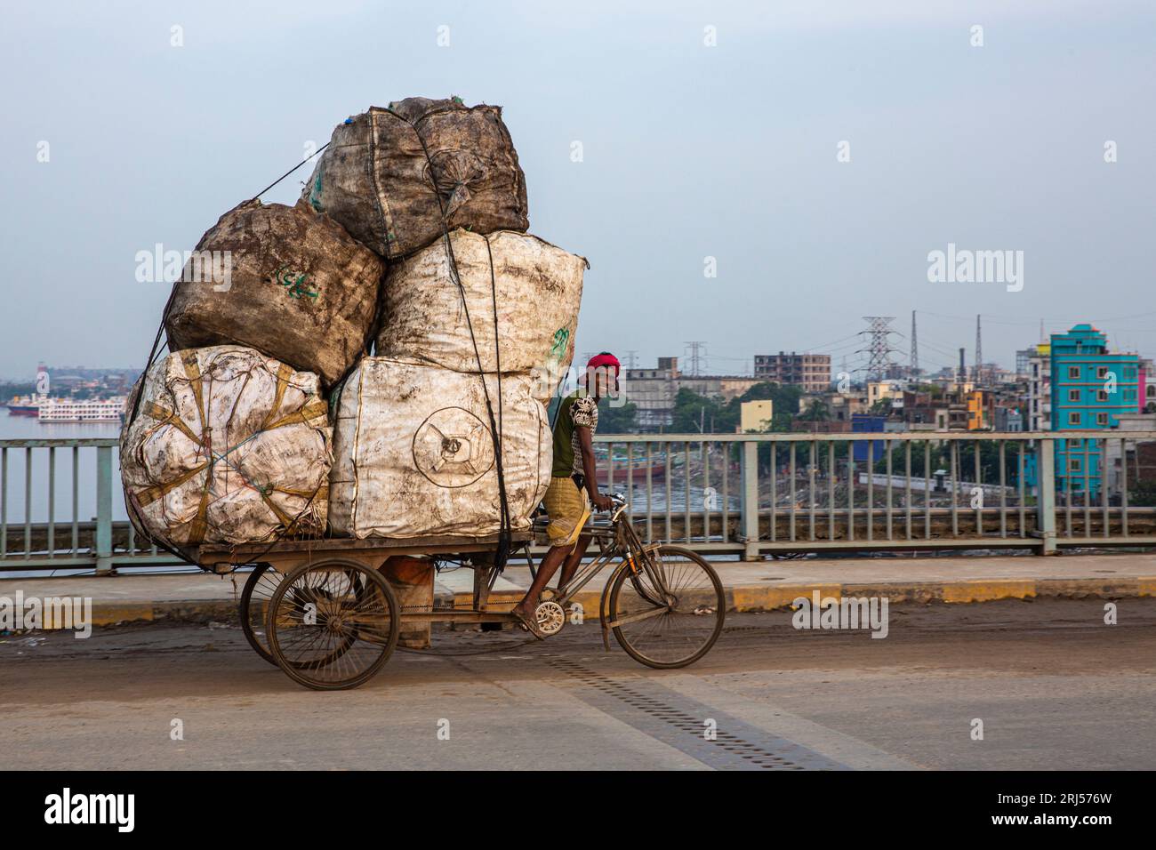 A rickshaw van transporting used plastic bottles to a plastic recycling center on the Bangladesh-Chaina Friendship Bridge over the Buriganga River. Dh Stock Photo