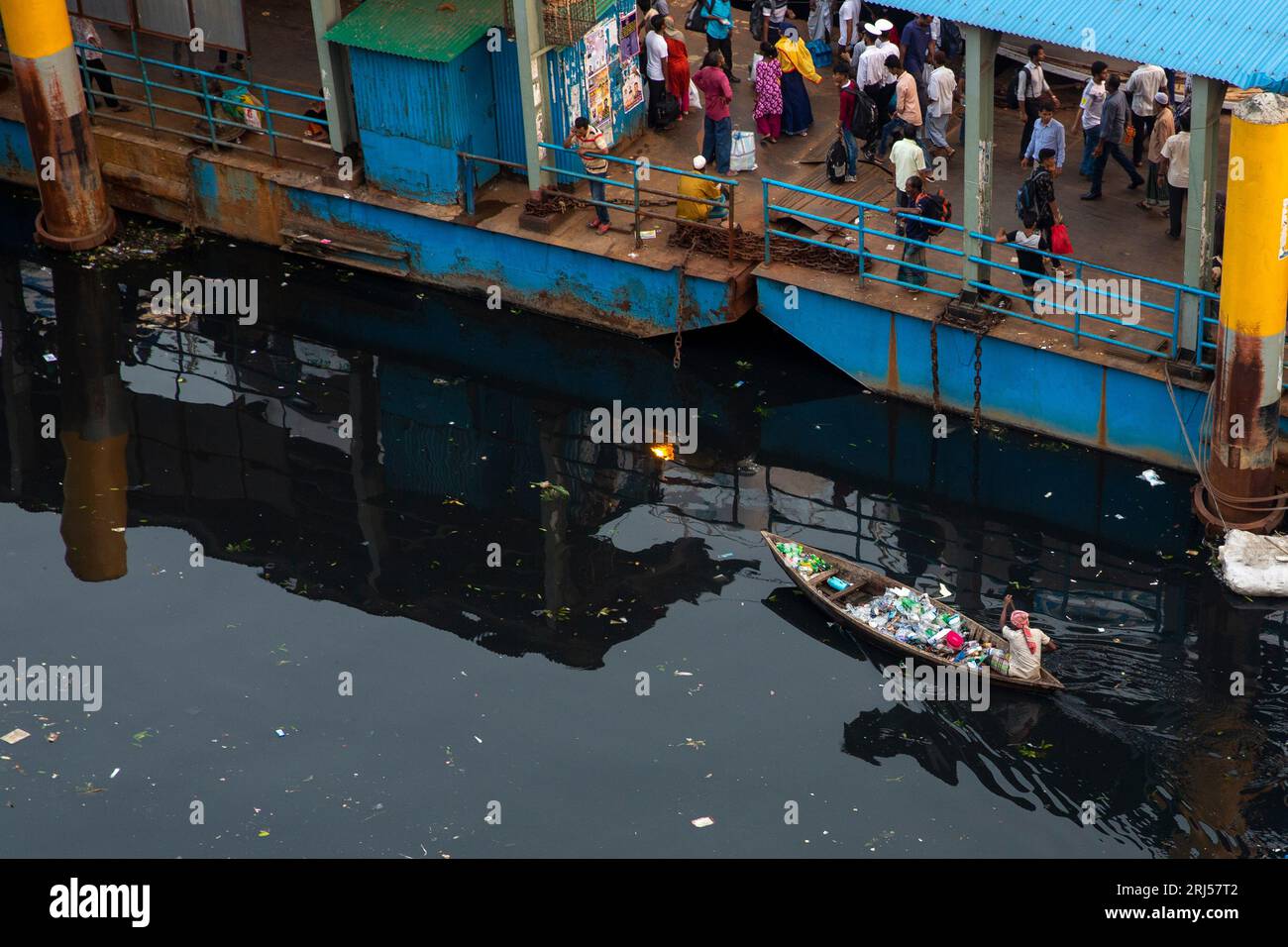 A man collects plastic garbage on his small boat form the Buriganga River near Sadarghat in Old Dhaka, Bangladesh. Stock Photo