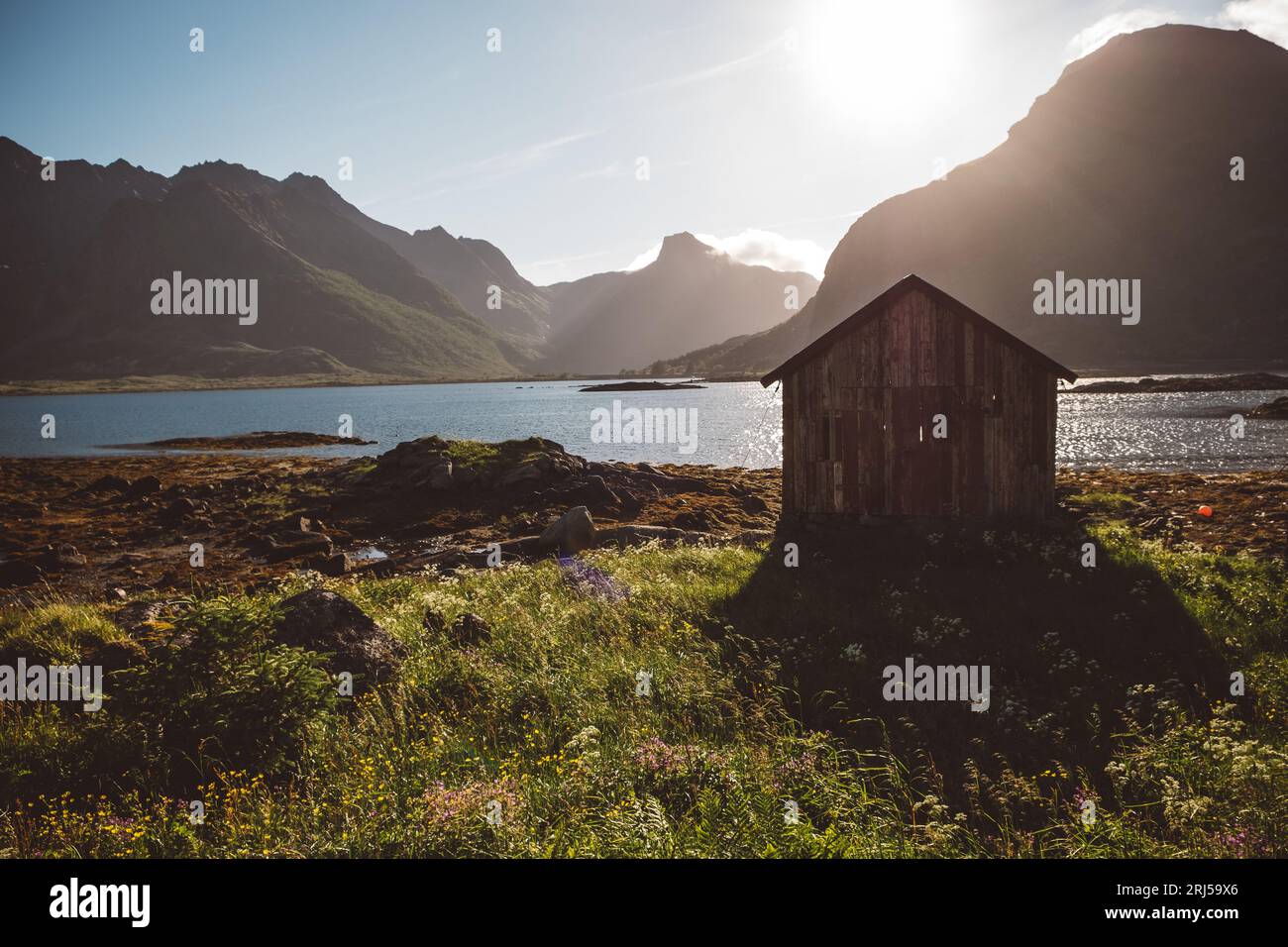 View of a wooden houseboy the lake surrounded by mountains Stock Photo