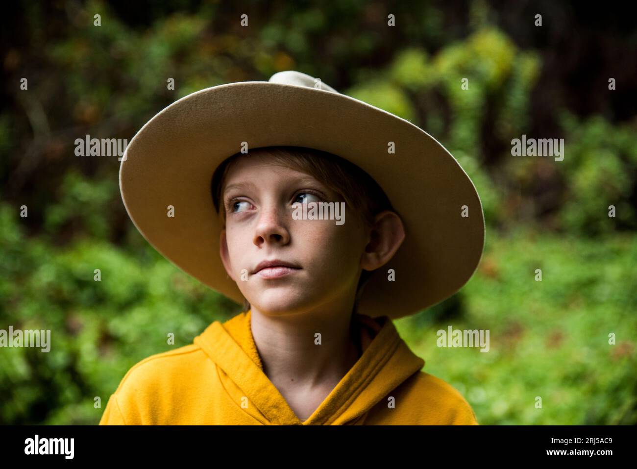 Young boy wearing big hat looking up and away Stock Photo