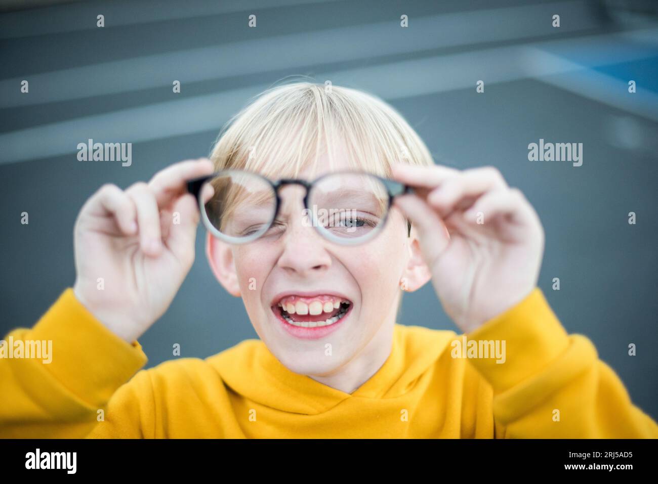 Young teenage boy playing with eyeglasses in front of his face Stock Photo
