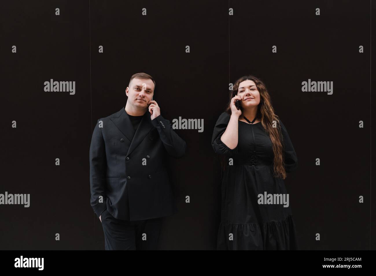 Young lovers woman and man in black clothes listen to audio message Stock Photo