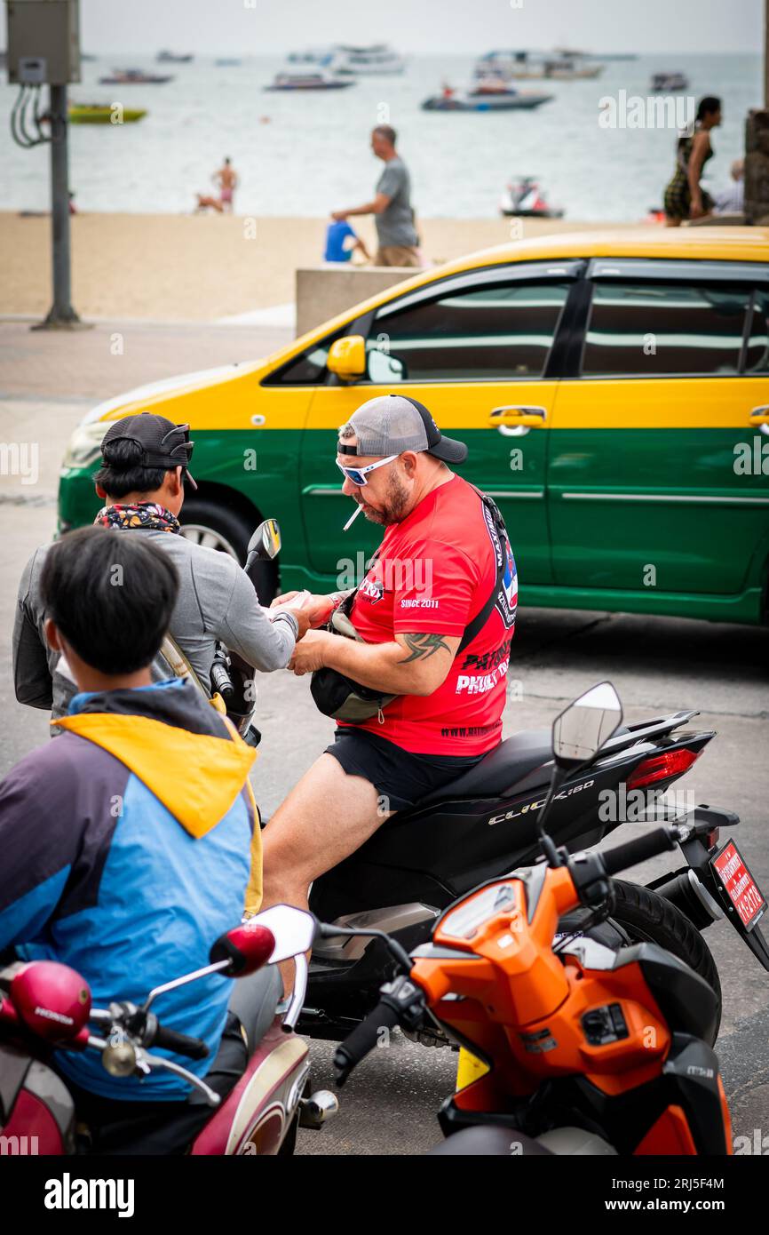 A man gets his driving licence checked whilst driving his motorbike along Beach Rd. Pattaya, Thailand. Stock Photo