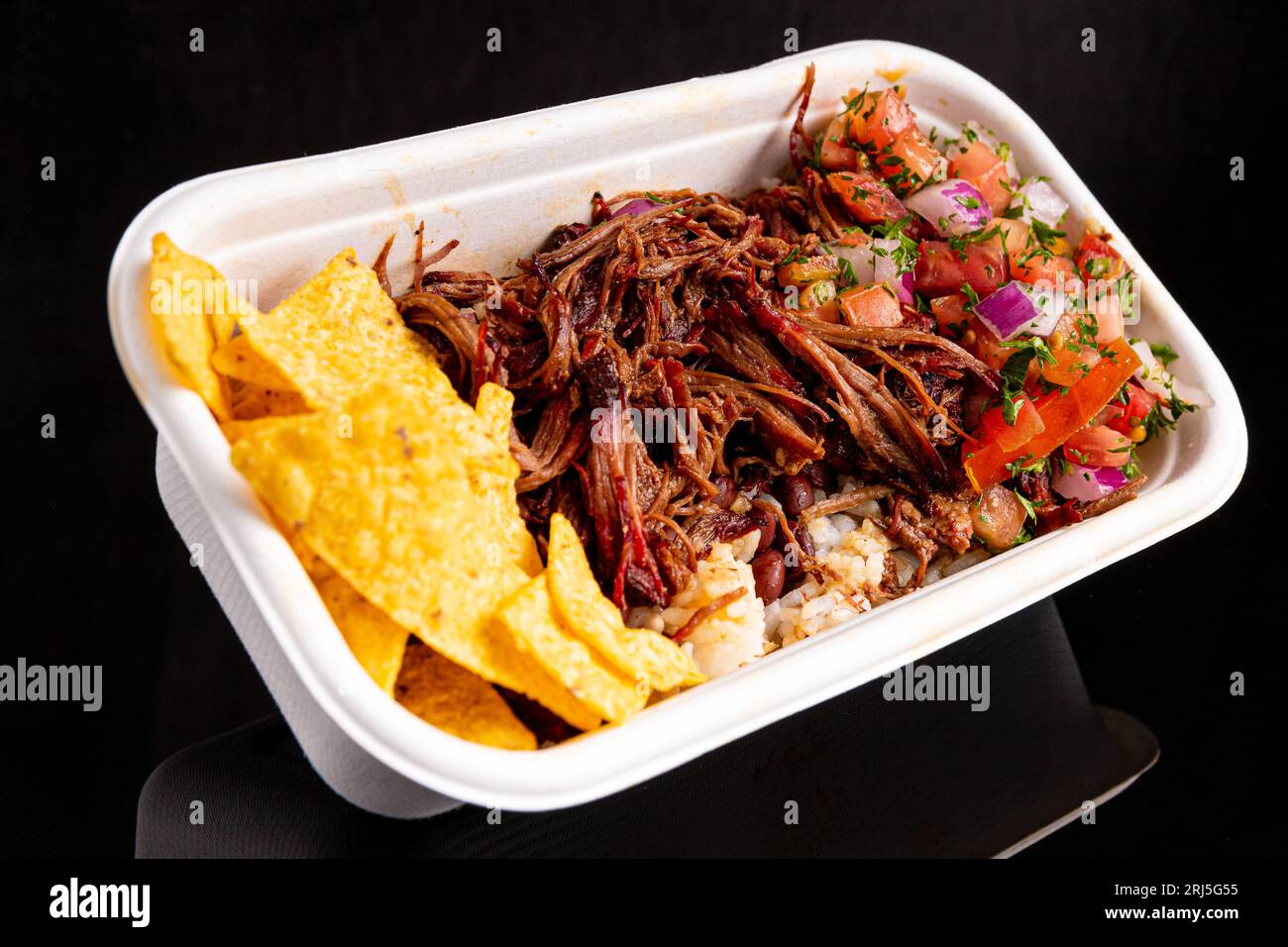 A closeup image of a plate with pulled beef, steamed white rice, and a side of salsa Stock Photo