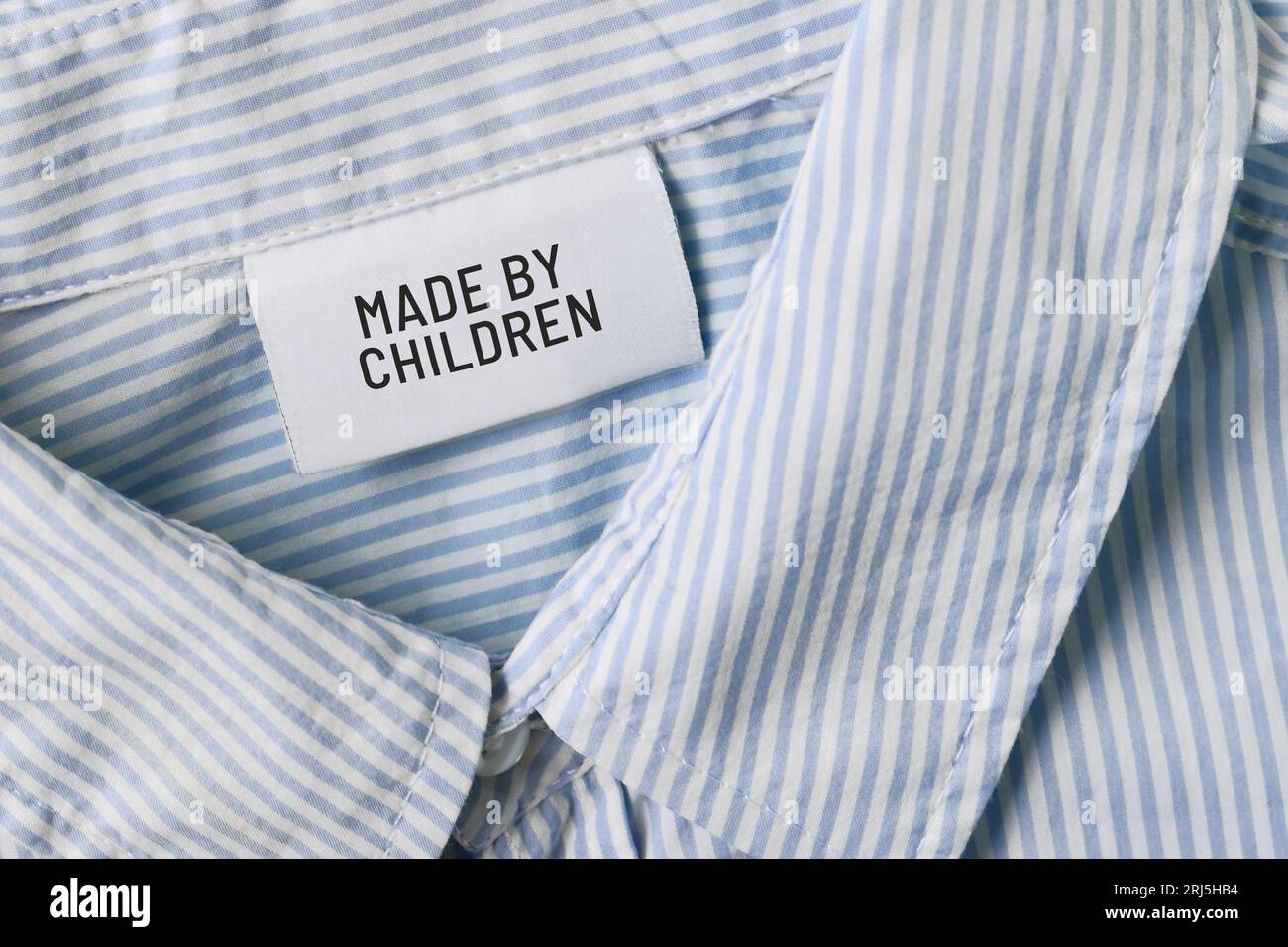 Clothing label with text saying 'Made by children'. Child labor concept Stock Photo