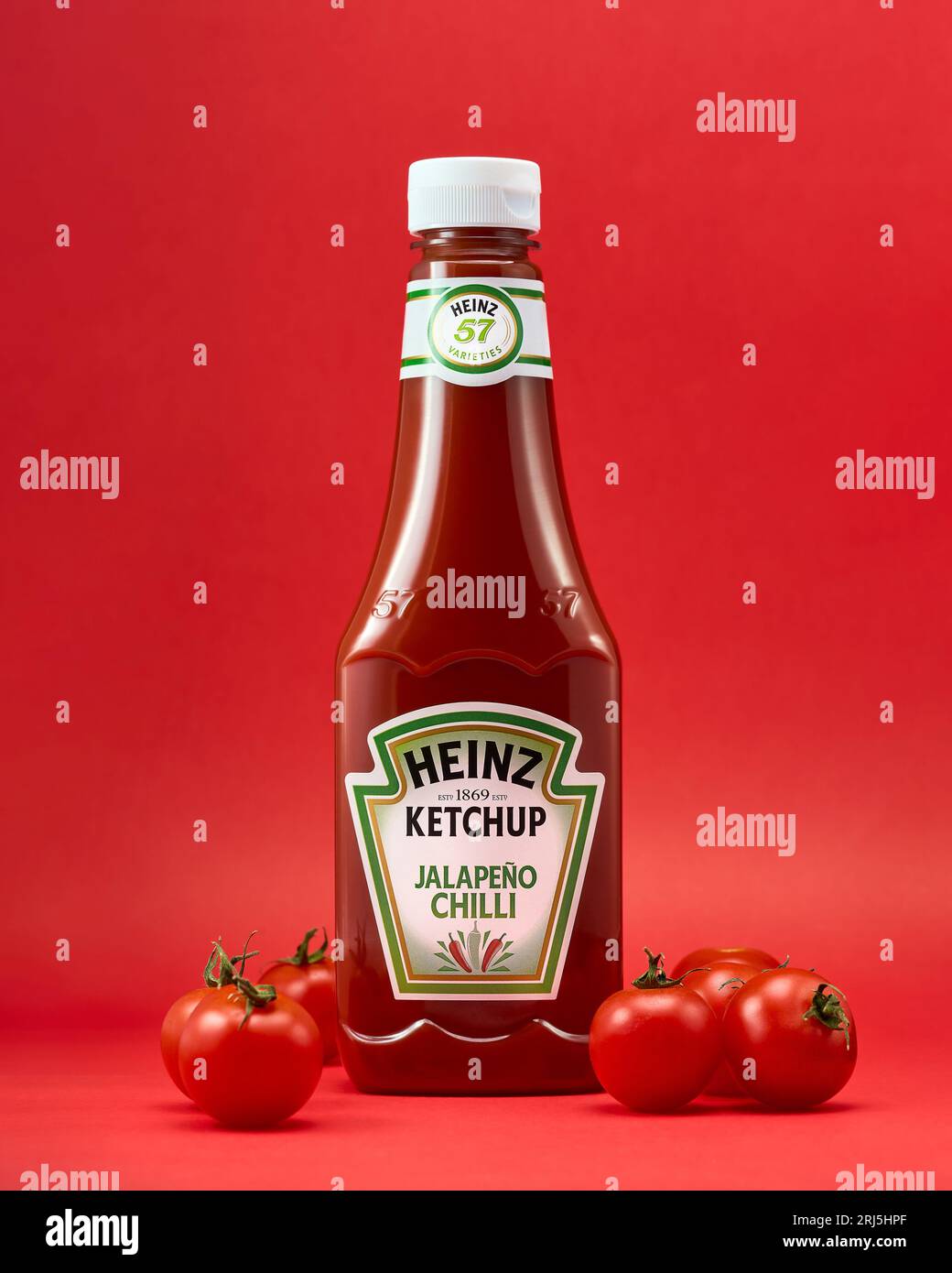 A bottle of Heinz Tomato Ketchup is positioned atop a vibrant red surface, creating an eye-catching display Stock Photo