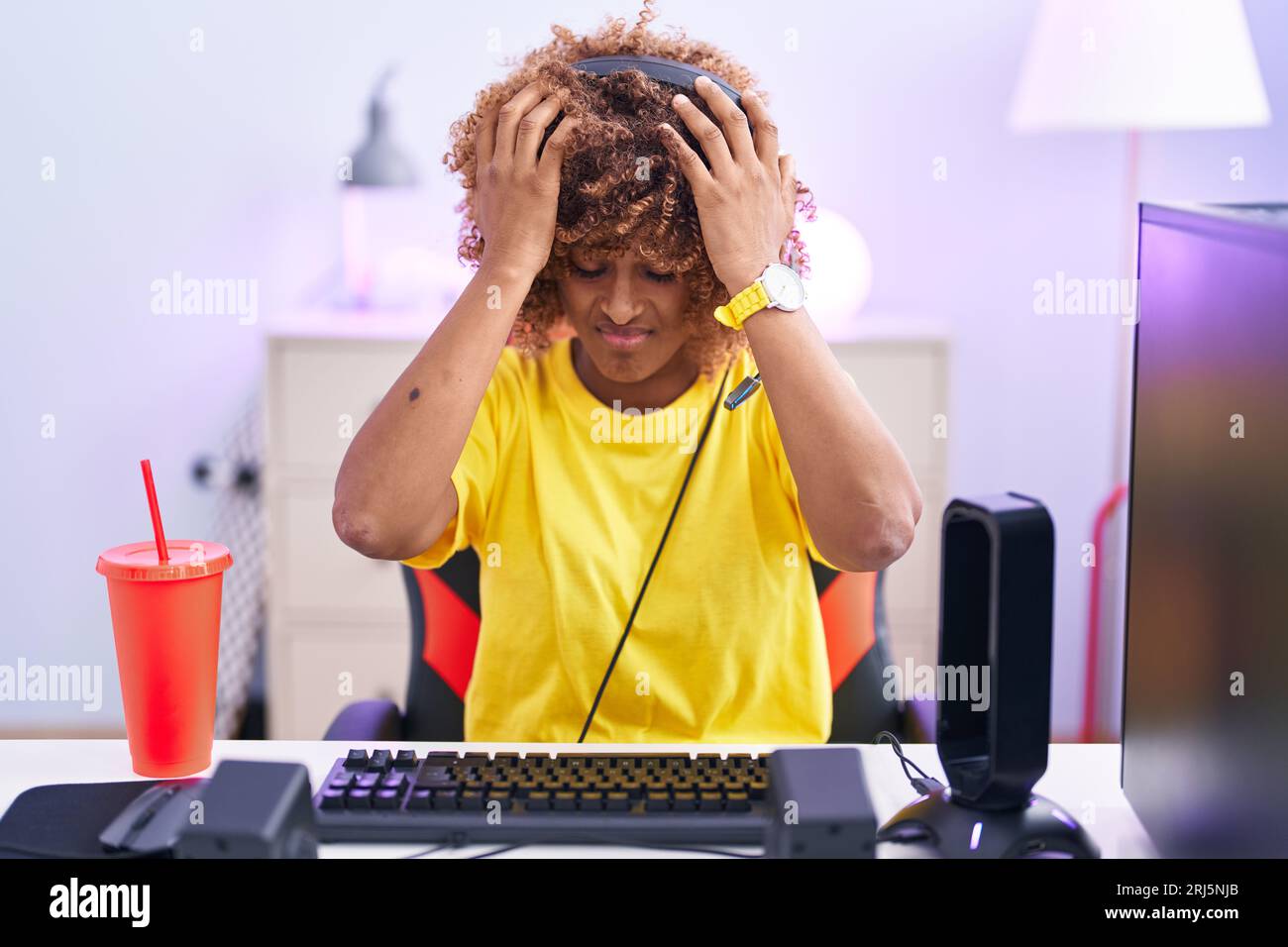 Young hispanic woman with curly hair playing video games wearing