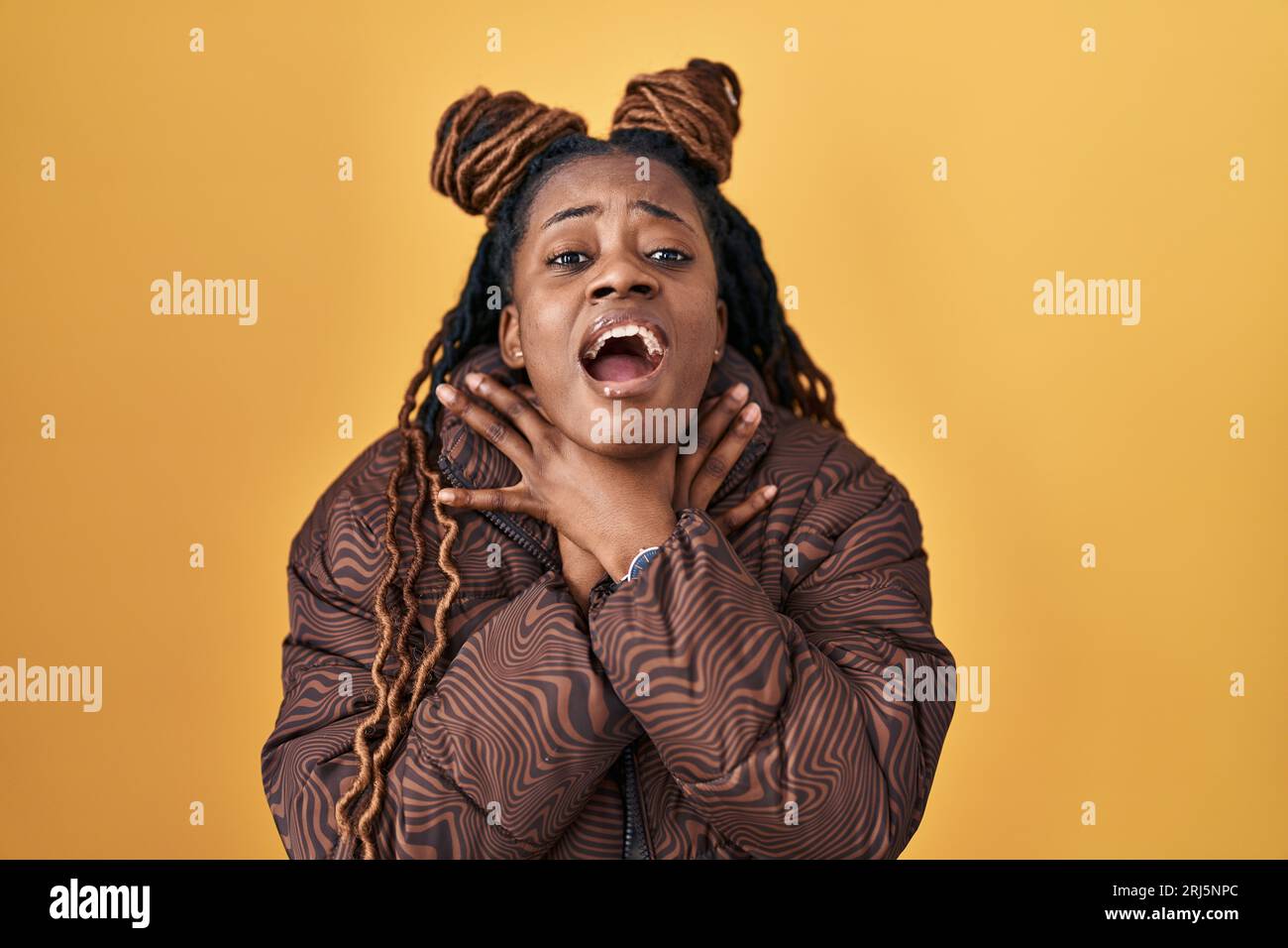 African woman with braided hair standing over yellow background shouting  suffocate because painful strangle. health problem. asphyxiate and suicide  co Stock Photo - Alamy