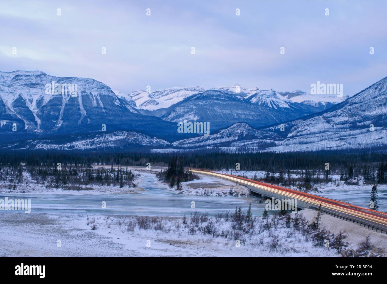 A long bridge passing over the frozen river in the winter landscape ...