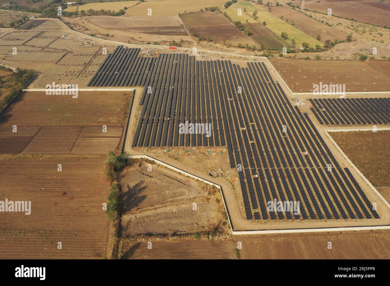 An aerial view of a rural landscape featuring a large solar array and ...