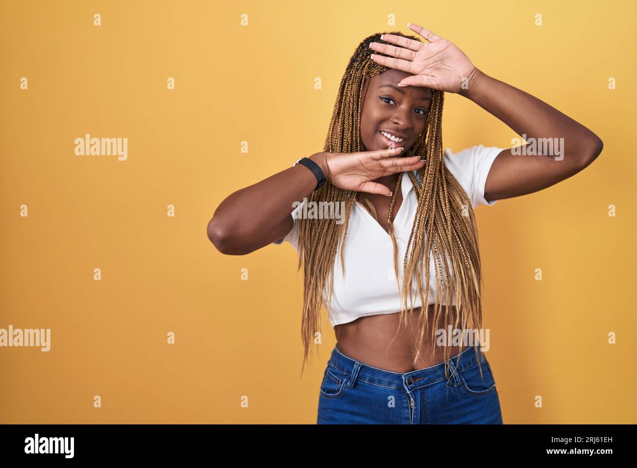 African american woman with braided hair standing over yellow ...
