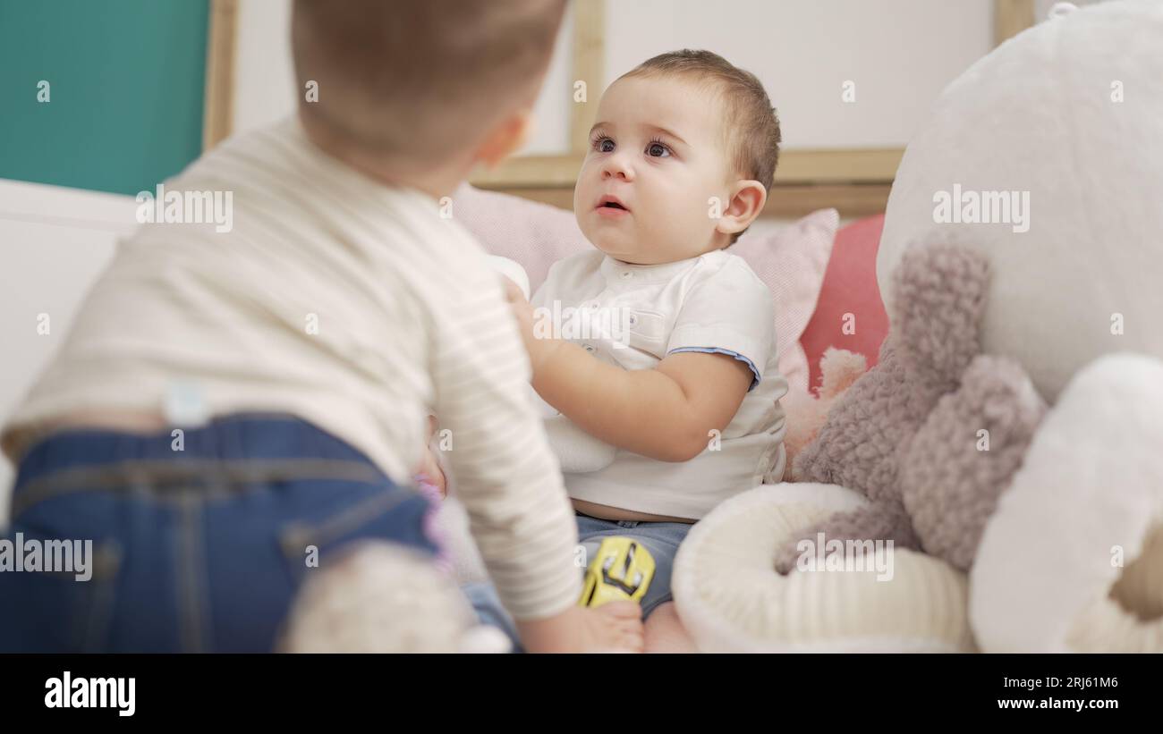 Two adorable toddlers sitting on bed playing at bedroom Stock Photo - Alamy