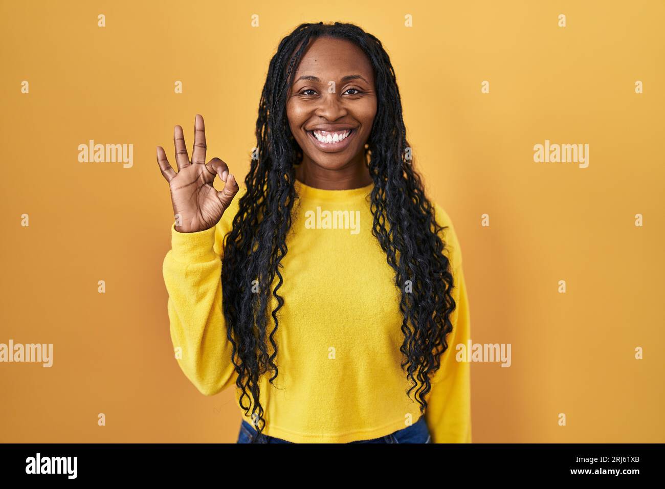African woman standing over yellow background smiling positive doing ok ...