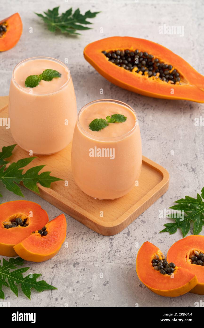 Fresh delicious papaya milk smoothie in glass cup on gray table background for tropical fruit design concept. Stock Photo