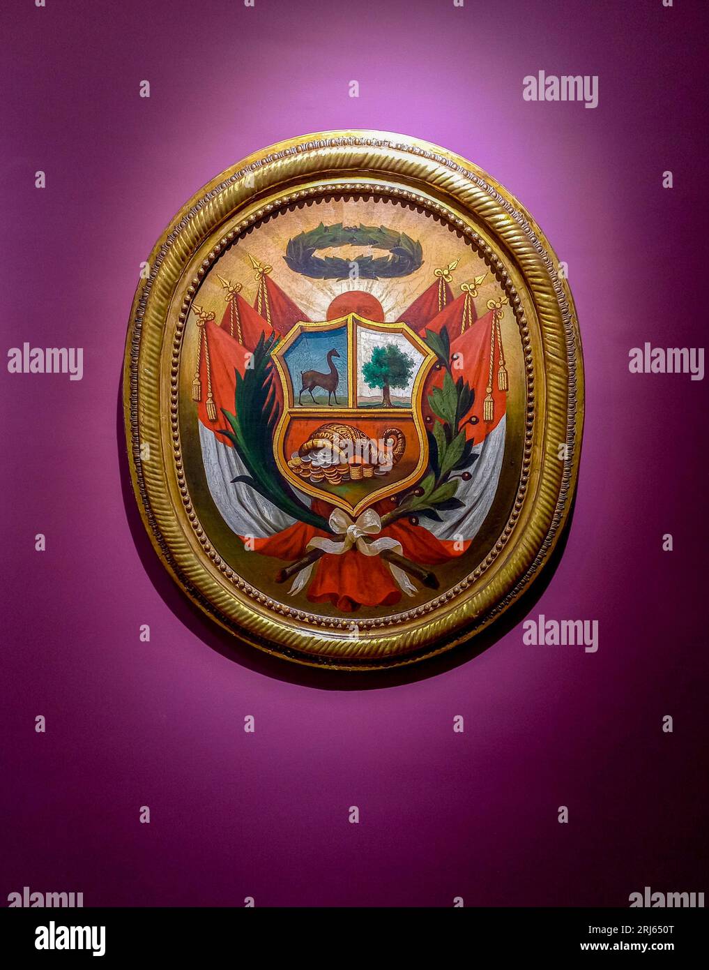 The coat of arms of Peru in a frame attached to a purple wall Stock