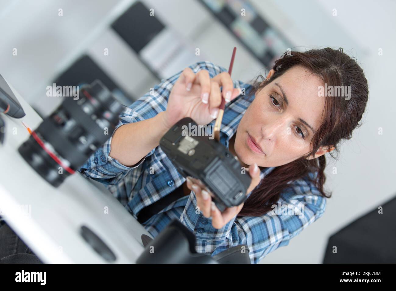 woman cleaning camera with brush Stock Photo