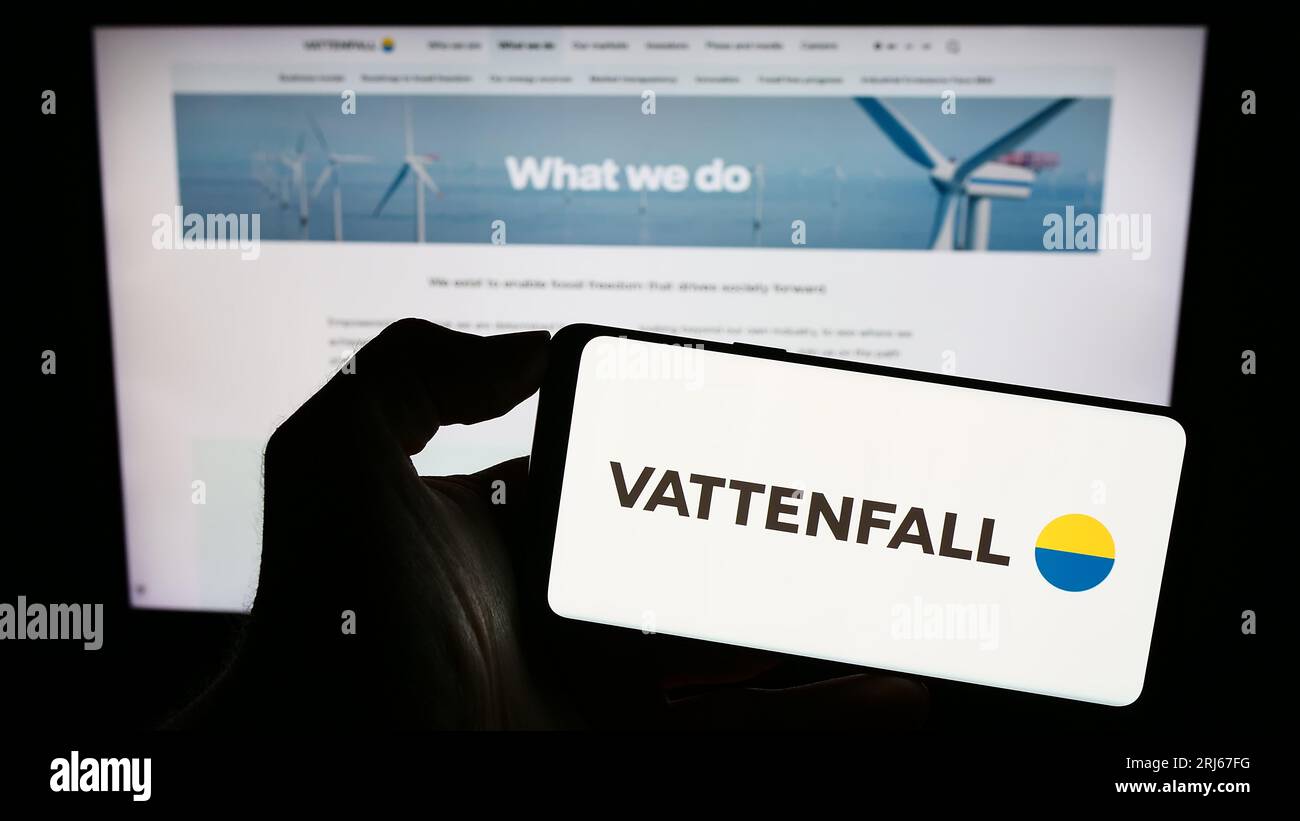 Person holding mobile phone with logo of Swedish energy company Vattenfall AB on screen in front of business web page. Focus on phone display. Stock Photo
