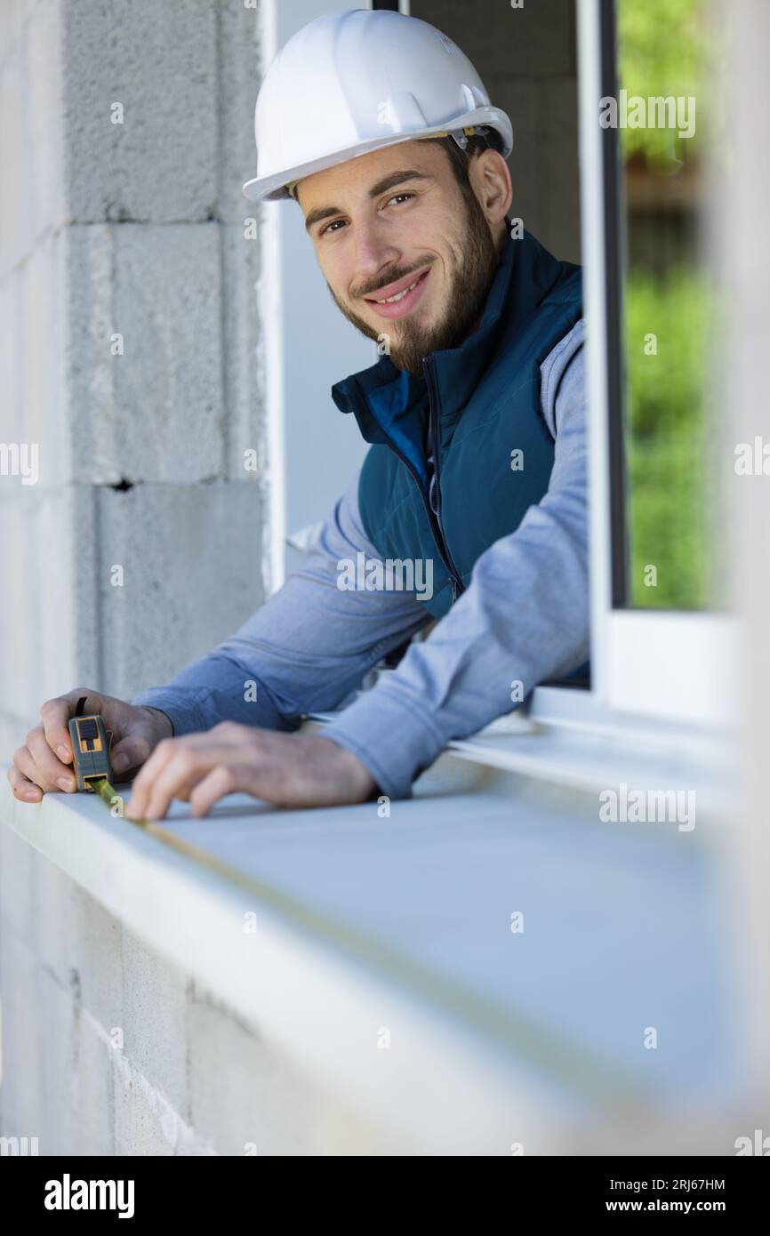 man worker in protective before installing sill on external window Stock Photo