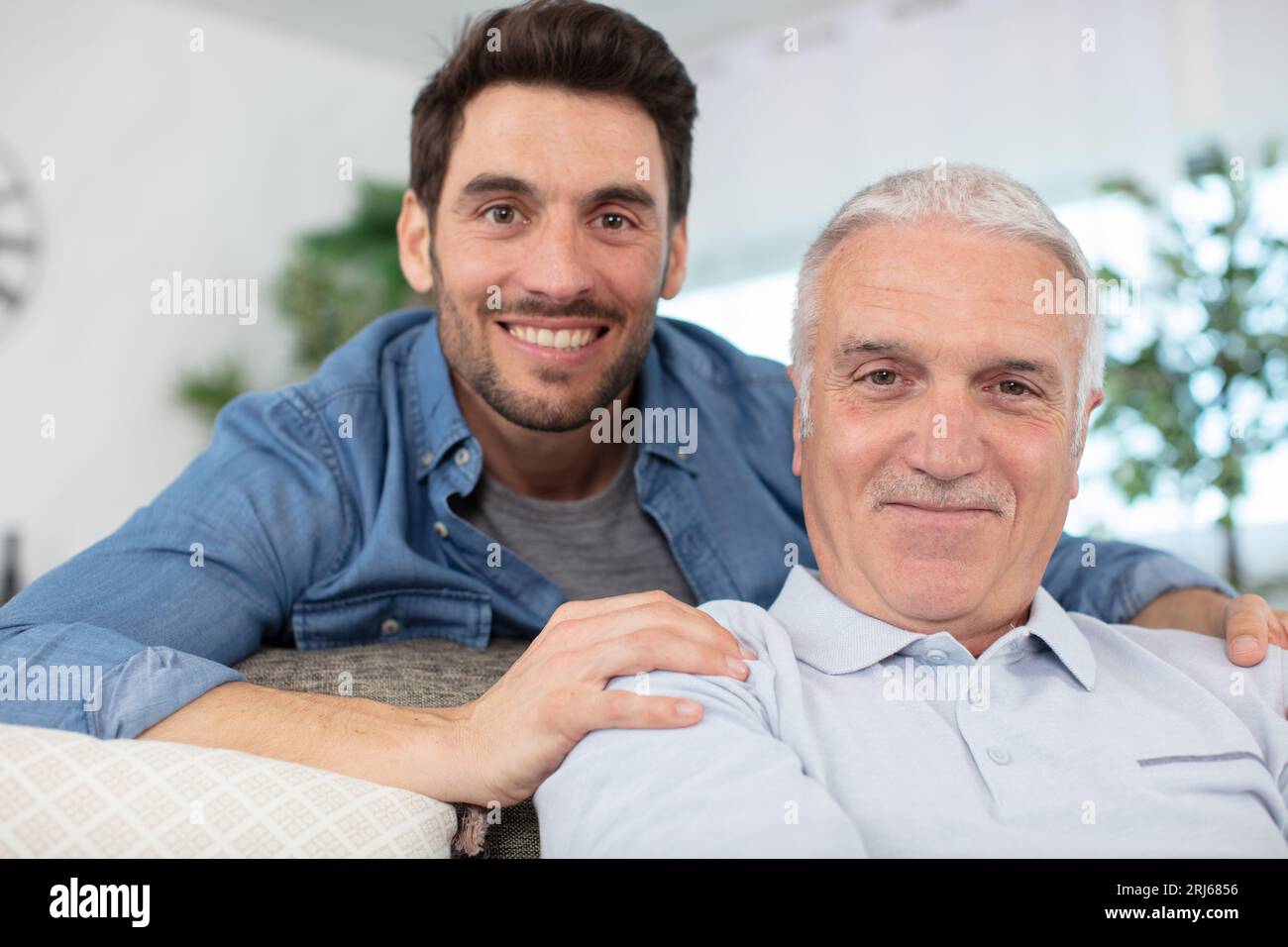 cheerful 60s father embrace grown up son Stock Photo