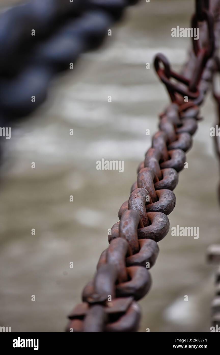 A distressed, rustcovered anchor rope with heavy chains draped across the surface Stock Photo