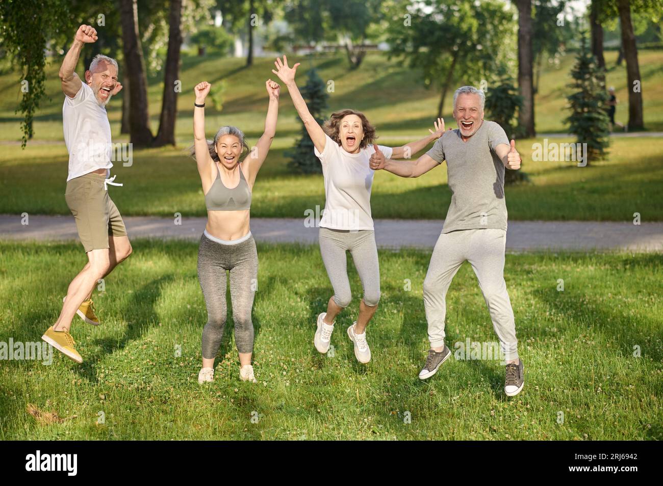 Group of healthy runners team jumping in the air at city park during ...