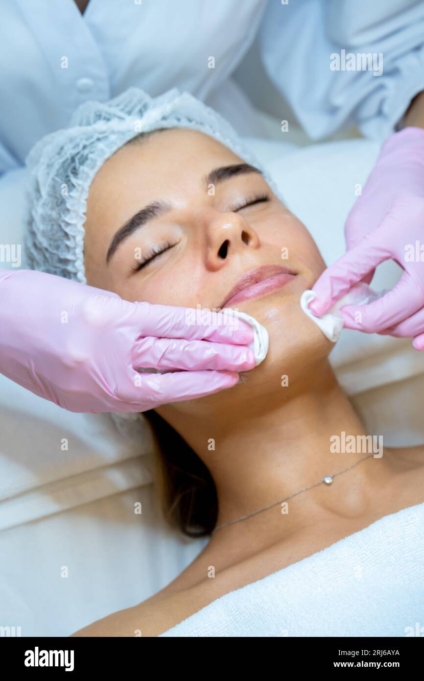 Beautician doctor cleaning woman face with cotton pads, skin care