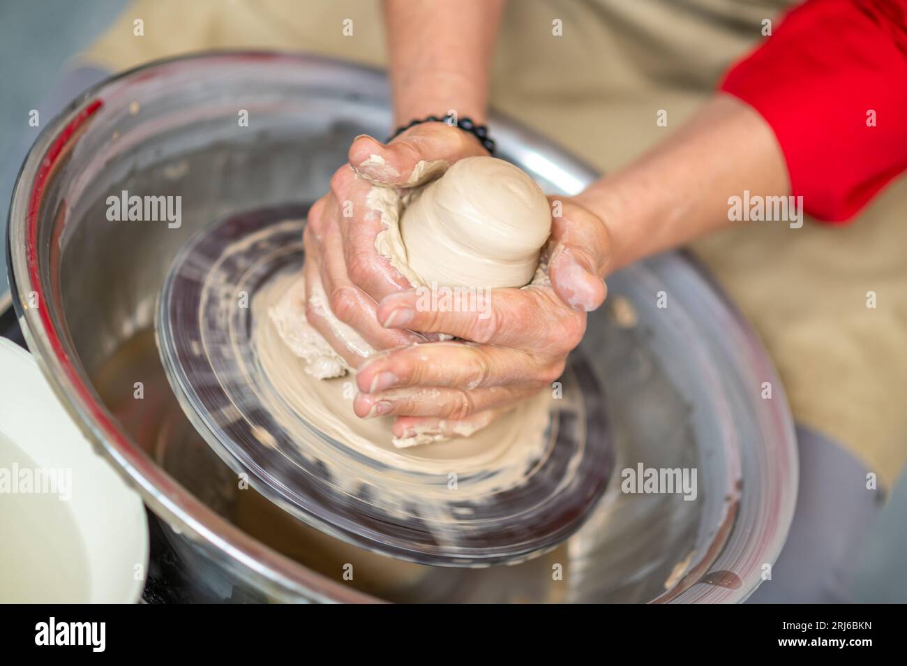 Woman working on potter's wheel in a pottery workshop, creating clay ...