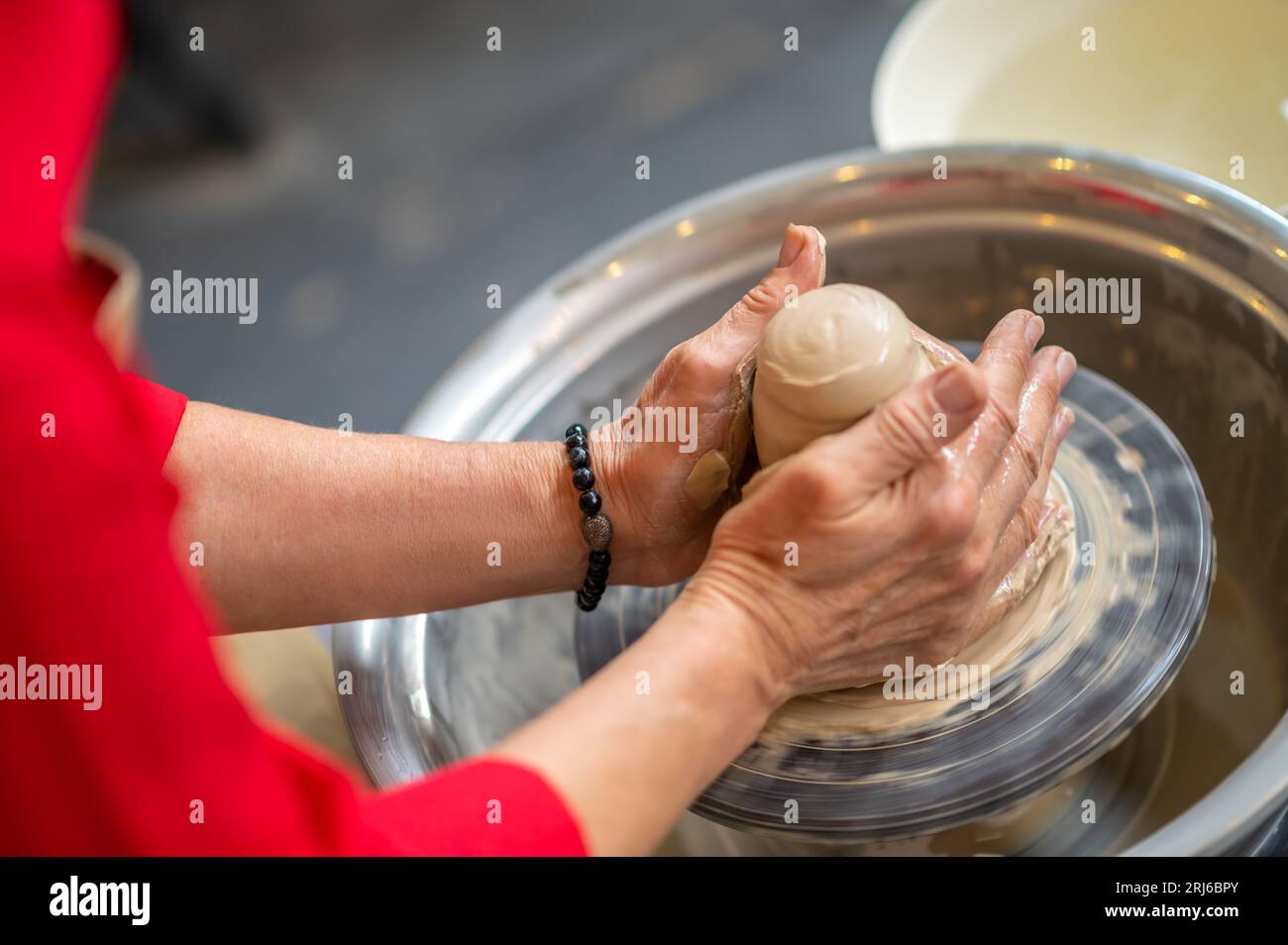 Woman working on potter's wheel in a pottery workshop, creating clay ...