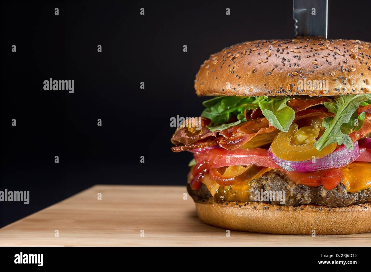 A close-up image of a large, freshly-prepared cheeseburger with lettuce and onions Stock Photo