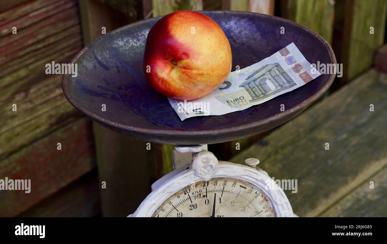 Old kitchen scale with a nectarine and a five Euro banknote. Stock Photo