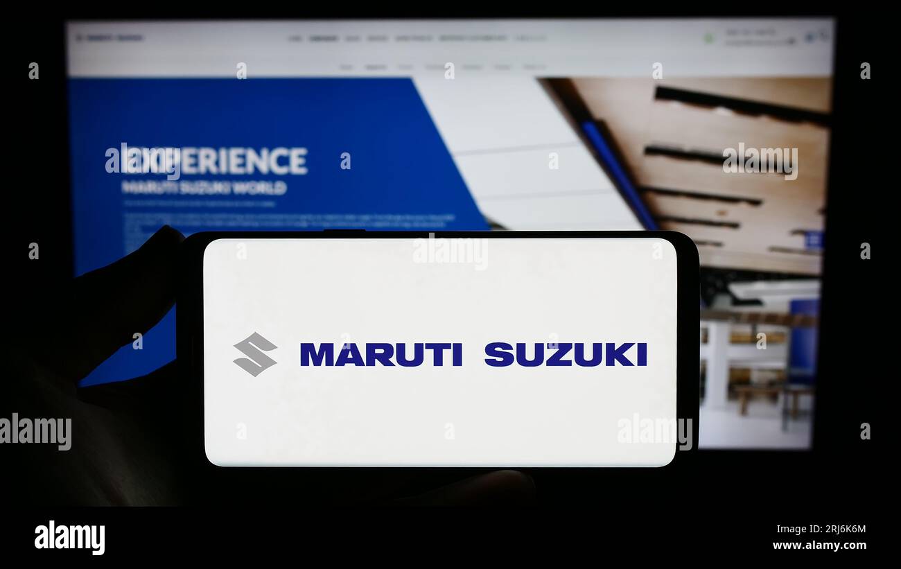 Person holding smartphone with logo of Indian company Maruti Suzuki India Limited on screen in front of website. Focus on phone display. Stock Photo