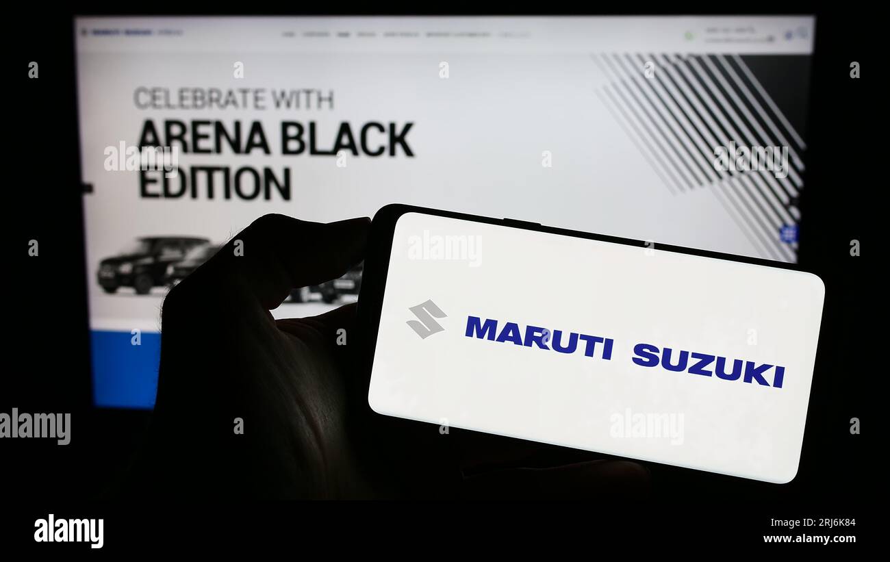 Person holding cellphone with logo of Indian company Maruti Suzuki India Limited on screen in front of business webpage. Focus on phone display. Stock Photo