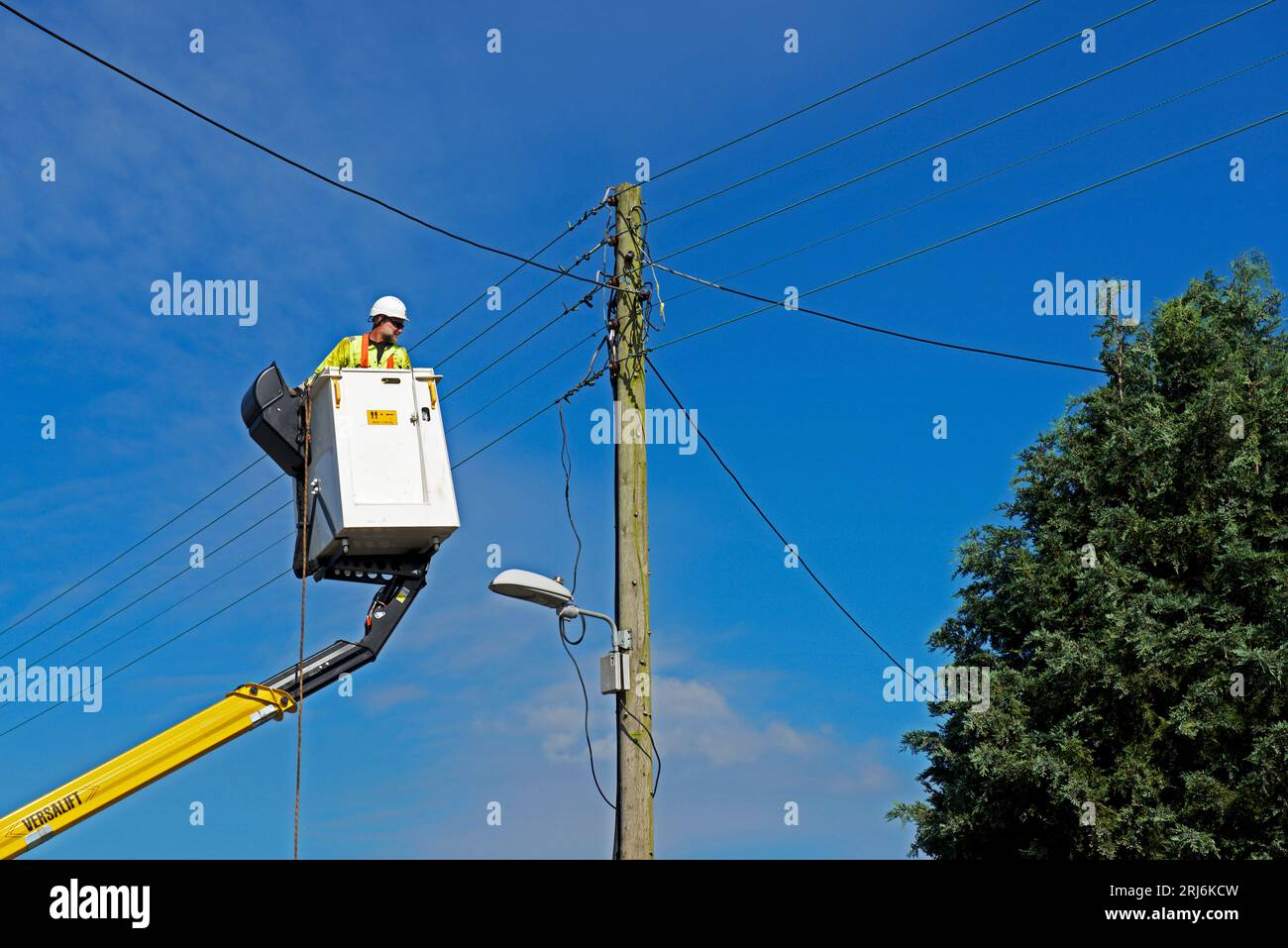 Contractors replacing telegraph poles and wiring in a village, England