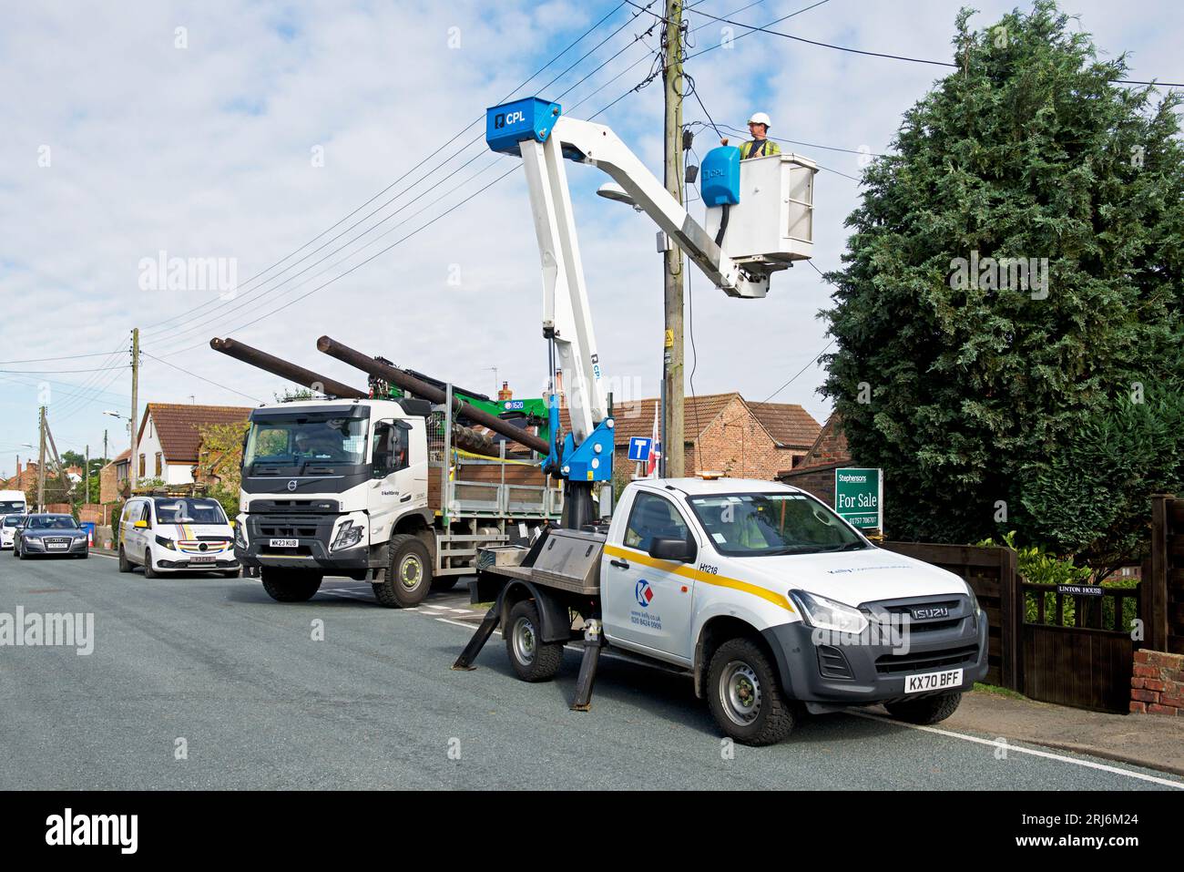Contractors replacing telegraph poles and wiring in a village, England
