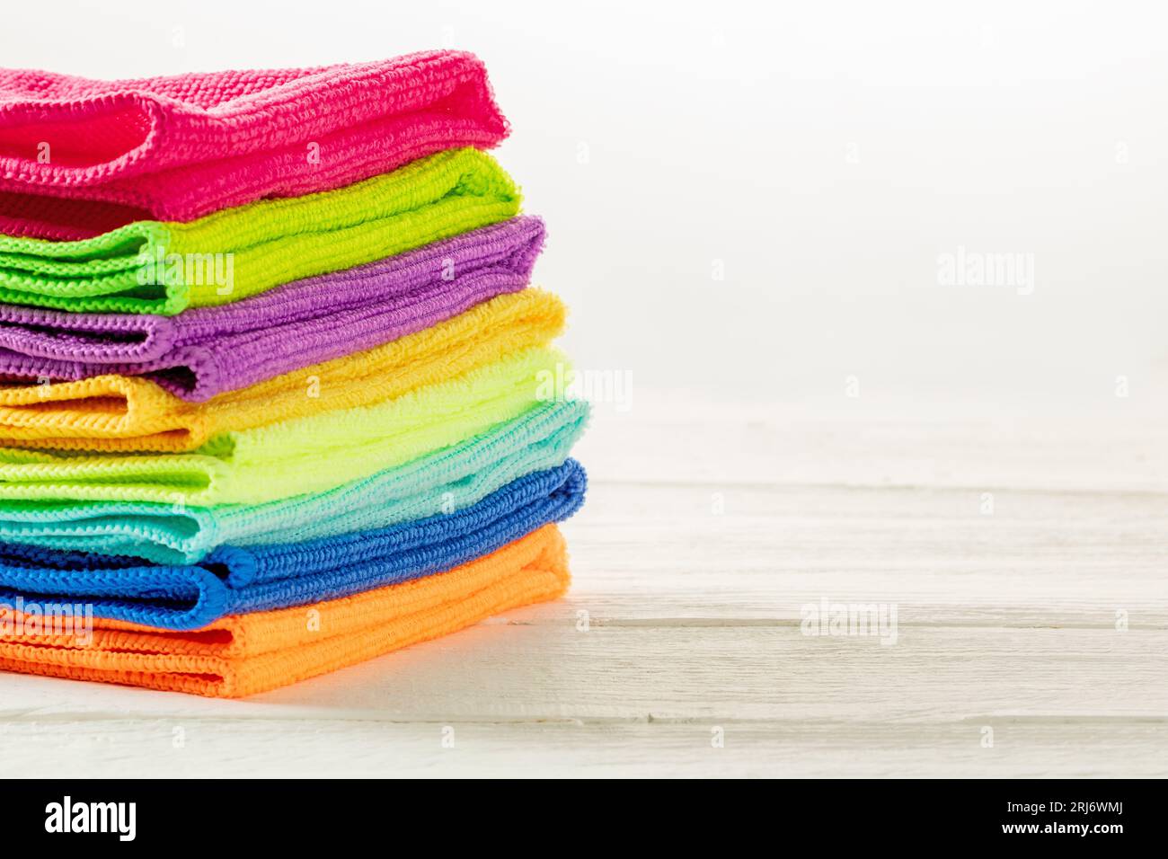 Stack of kitchen microfiber towels in bright colors on a white wooden background. Stock Photo