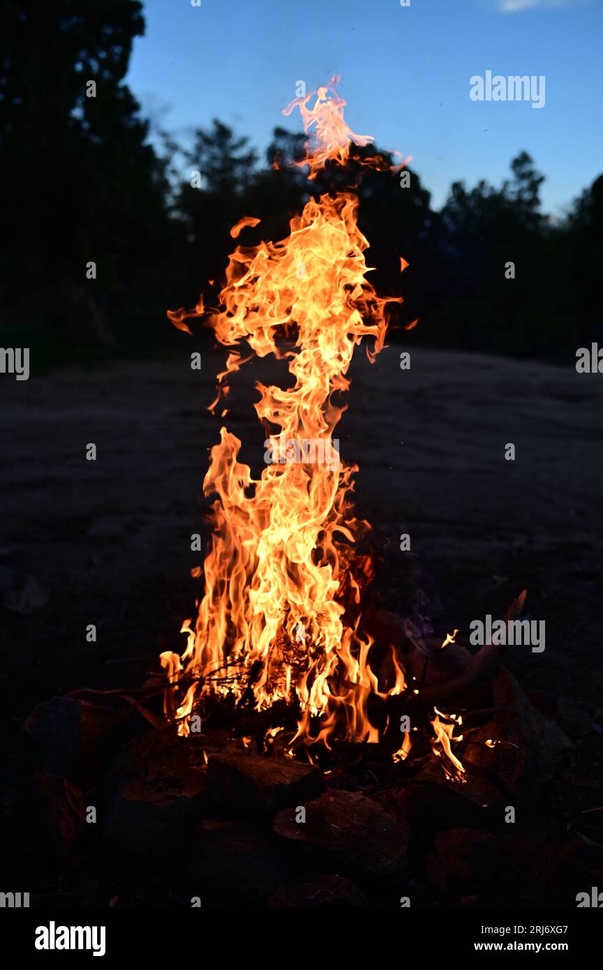 A mesmerizing scene of an intense fire burning brightly against a night sky, with smoke rising from the flames Stock Photo