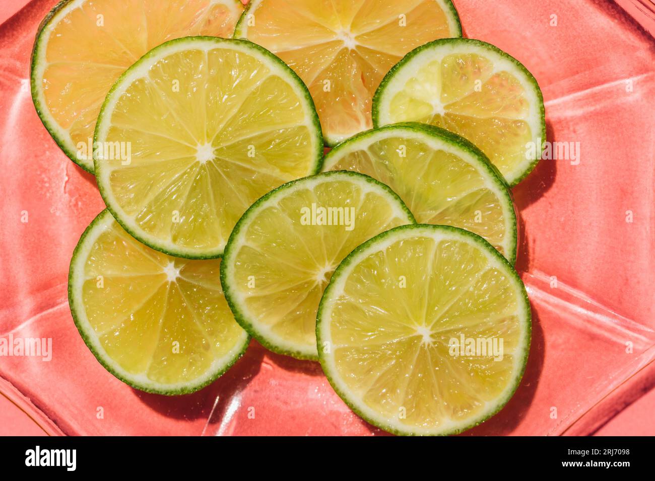 bright green sliced lime wheels on pink glass plate with pink ...