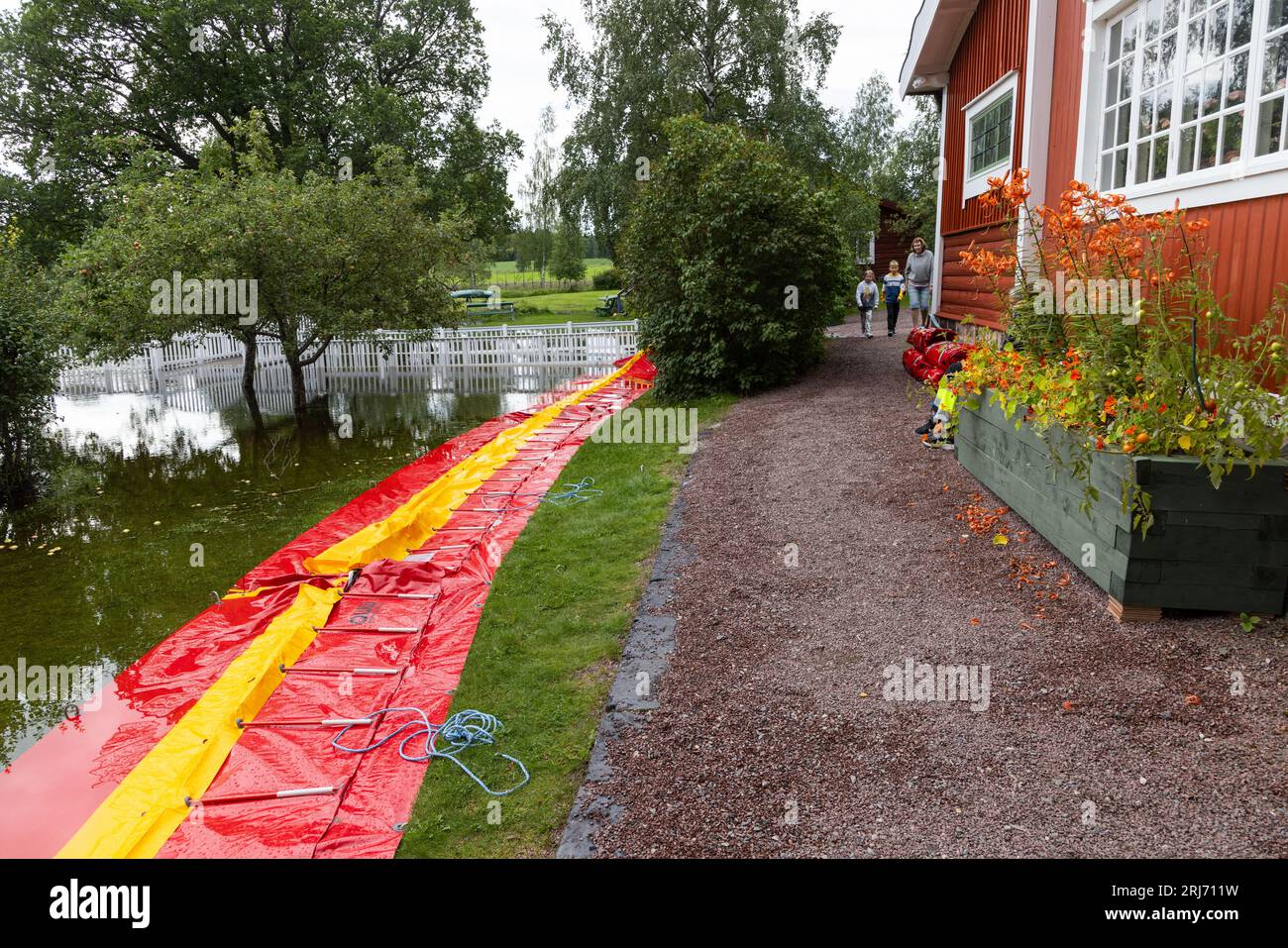 The Carl Larsson house in Sundborn, Dalarna County, Sweden. Sundborn is a locality situated in Falun Municipality, Dalarna County. The most famous resident was the painter Carl Larsson and his house (Little Hyttnäs) in Sundborn is a popular tourist attraction. In the picture: Flooded Sundborn river just outside The Carl Larsson house. Here a water protection equipment from QWW company. Stock Photo