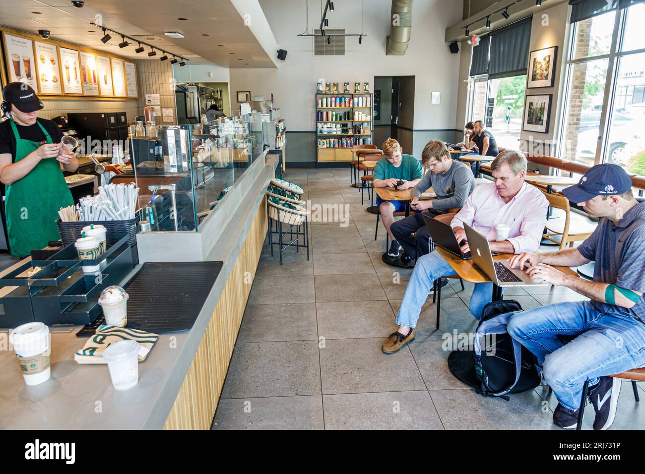 Augusta Georgia,Starbucks Coffee,inside interior indoors,barista preparing orders,customers using laptops working,man men male,adult,residents,inside Stock Photo