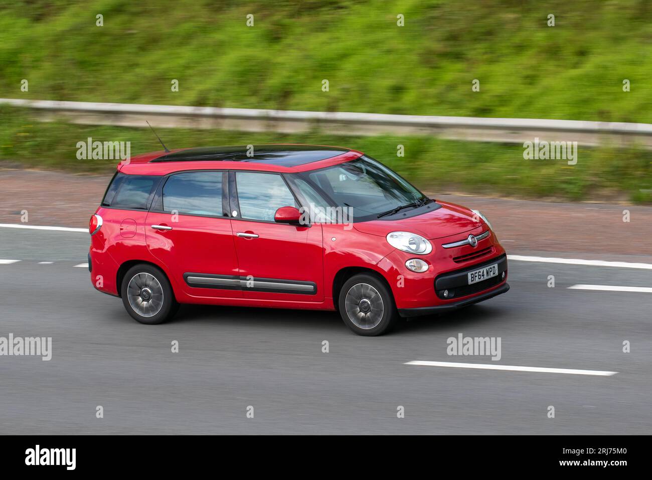 2014 Red Fiat 500L 1.3 MultiJet Lounge MPW Dualogic Euro 6 (s/s) 5dr (7 Seat) ; travelling at speed on the M6 motorway in Greater Manchester, UK Stock Photo