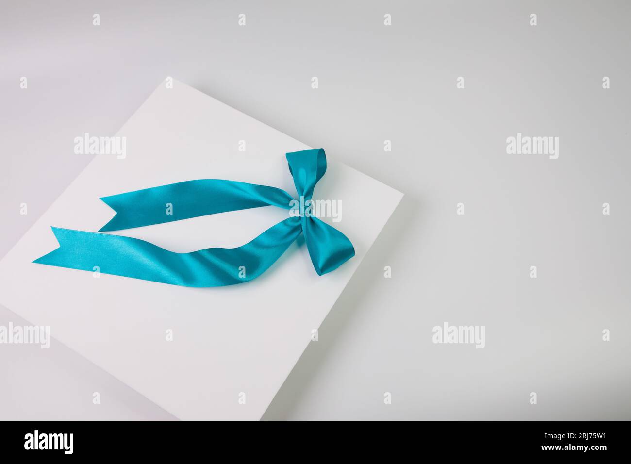 A high-resolution closeup image of a blank white card with a blue bow tied around it Stock Photo