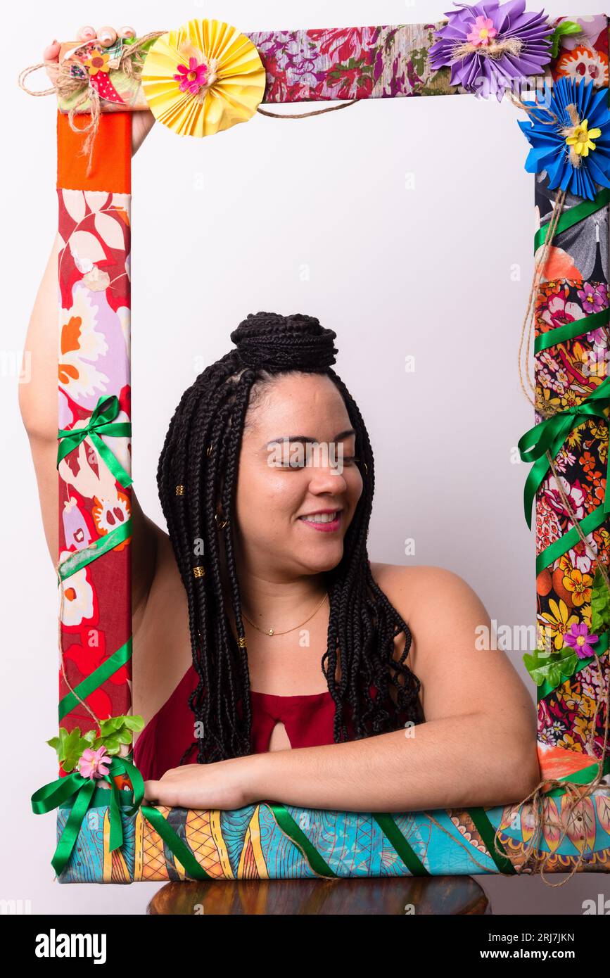 Beautiful woman behind a frame adorned with flowers and colorful cloths ...