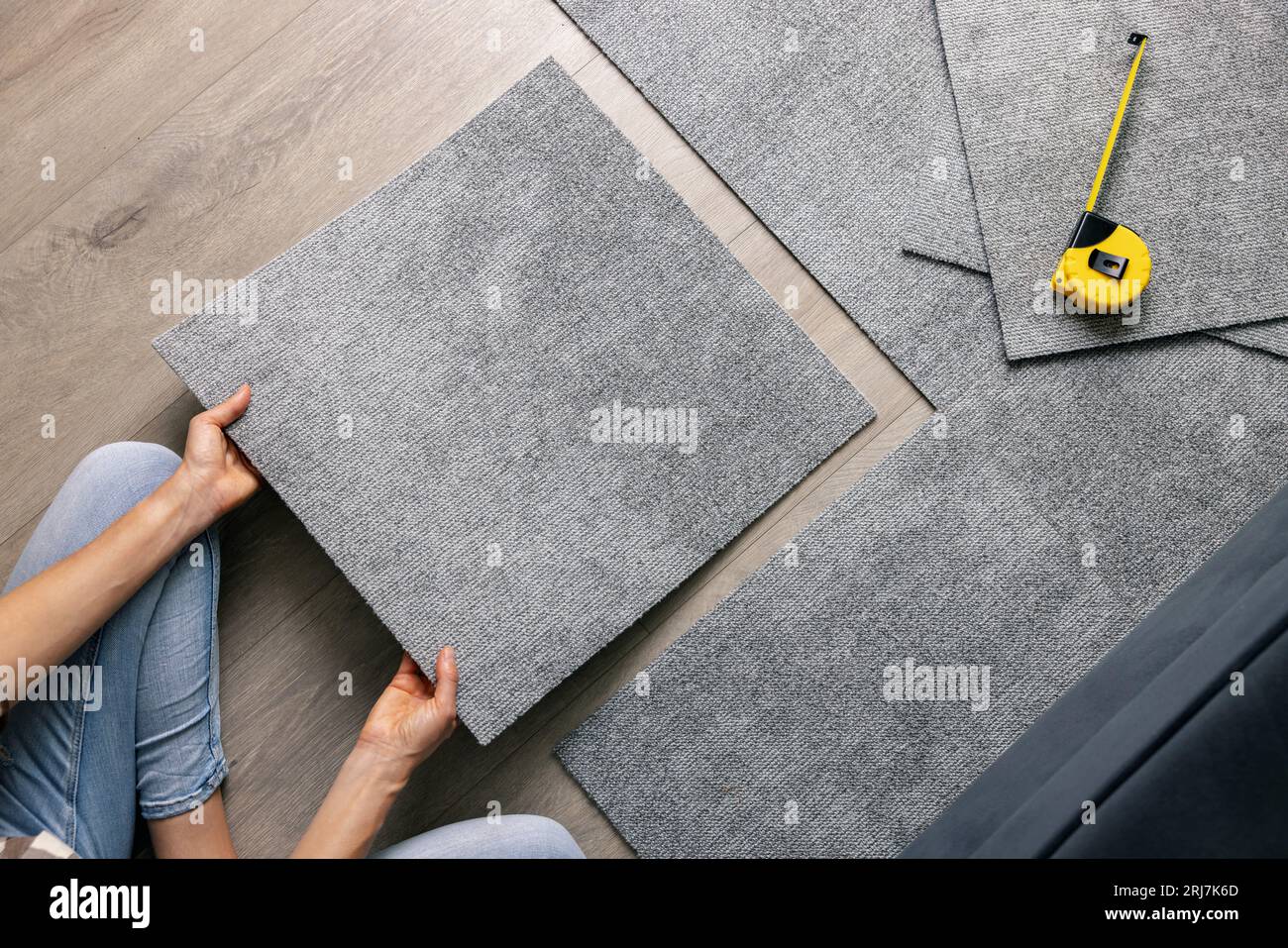 woman laying carpet tiles on floor in living room. diy home improvement Stock Photo