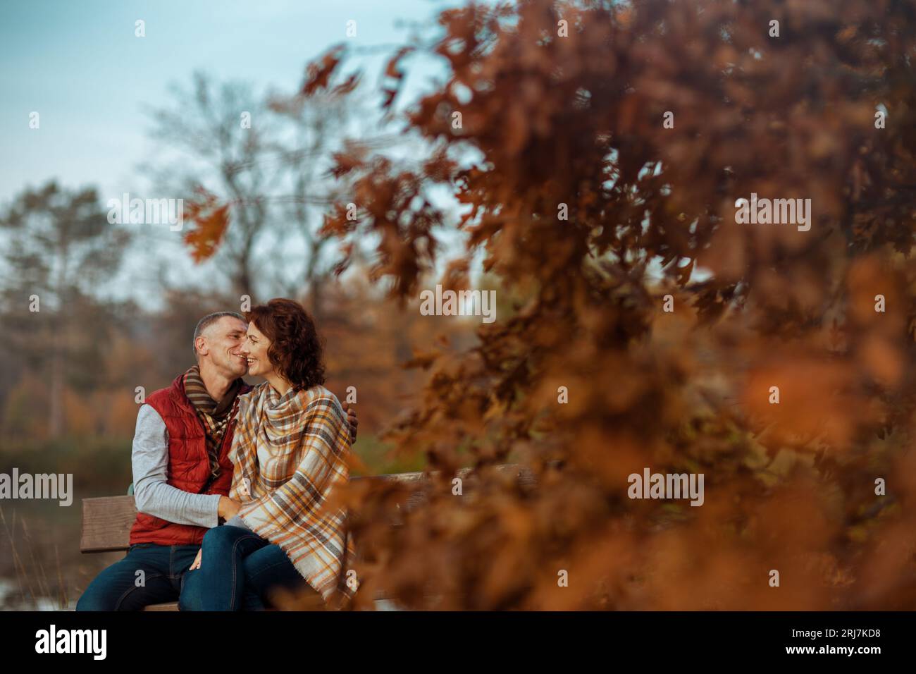 Hello autumn. smiling modern couple in the park kissing while sitting ...