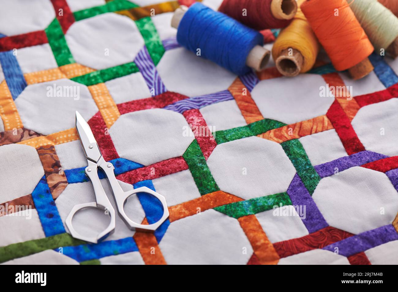 Scissors and spools of thread lying on fragment quilt top sewn by hand ...